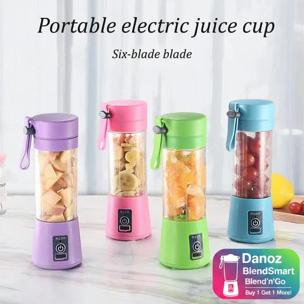Four portable electric juice cups in different colors with fruits inside, on a light surface.
