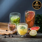 Four glass cups with different fruit-infused drinks on a wooden surface.