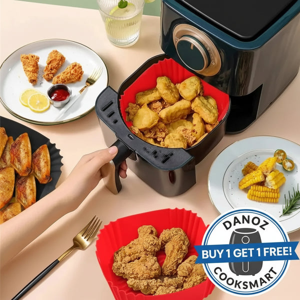 Air fryer with food on a table, including plates of fried chicken and corn on the cob.