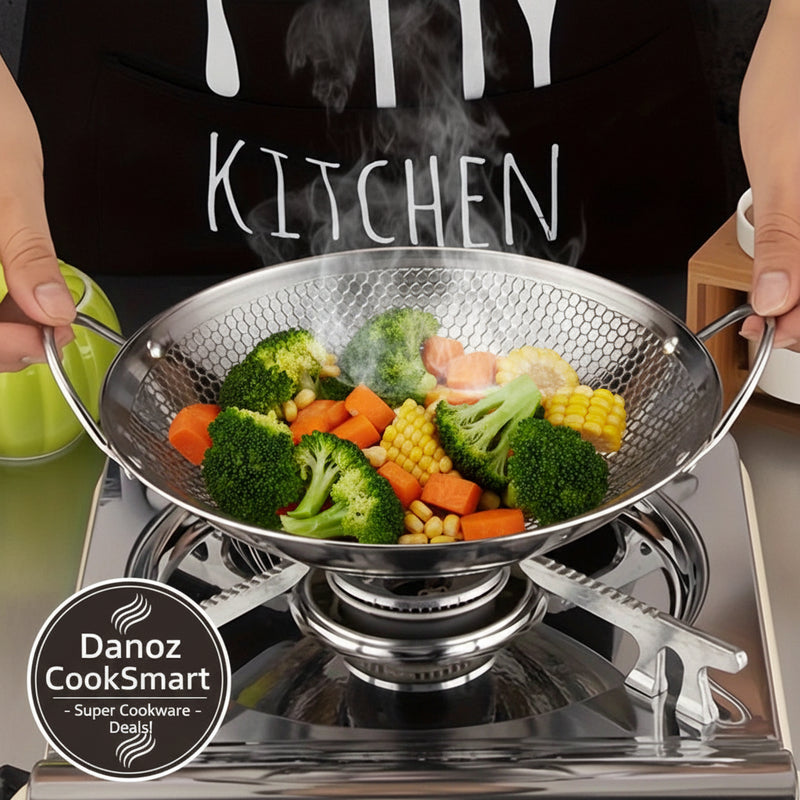 Metallic wok on a stove with a person wearing a black apron with 'KITCHEN' text.