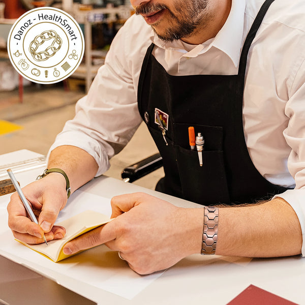 Person wearing a black apron writing in a notebook with a pen.
