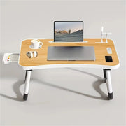 Wooden desk with laptop, coffee cup, and other items on a light gray background
