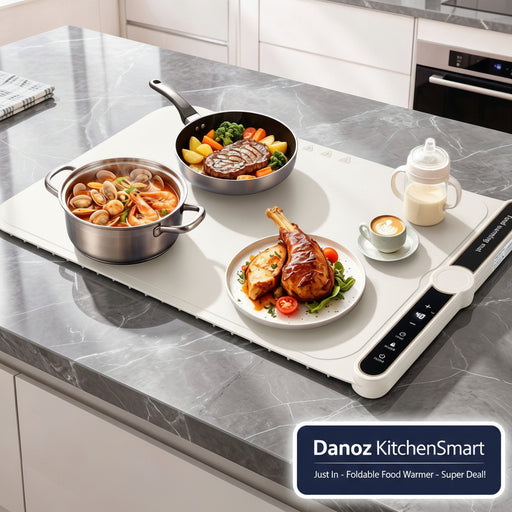 A white smart cooktop with a black control panel is set on a gray marble kitchen countertop. The cooktop is styled with various meals, including a pot of clams, a skillet with steak and vegetables, and a plate of roasted chicken, alongside a baby bottle and a cup of coffee.