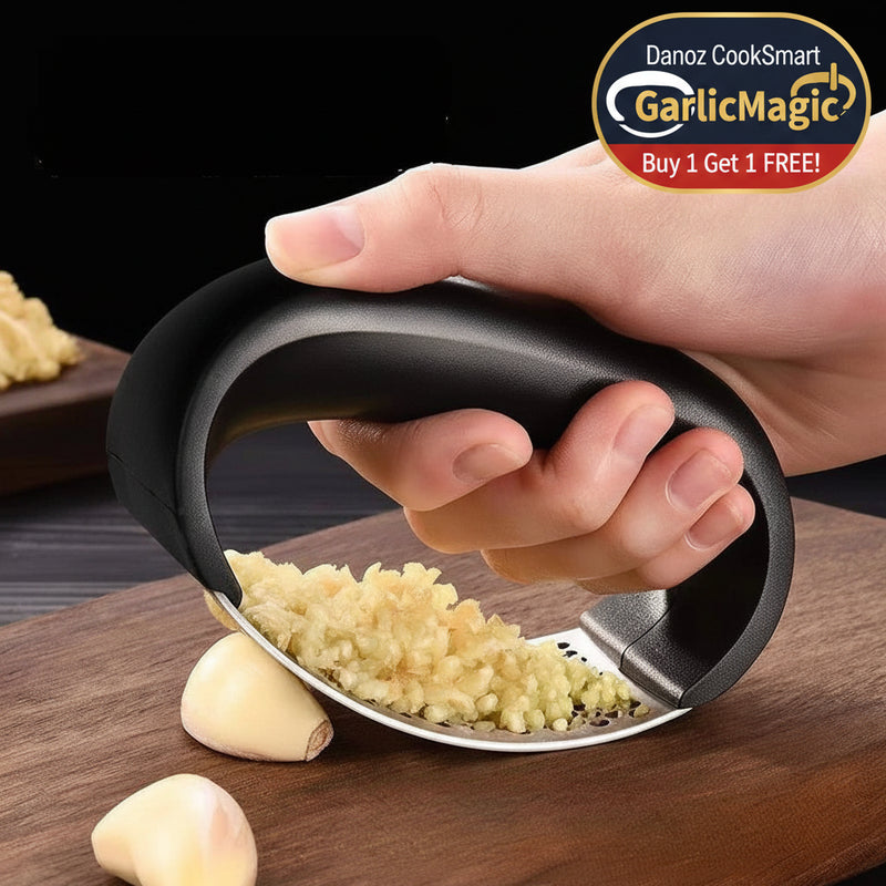 Hand using a garlic press on a wooden cutting board with garlic cloves.