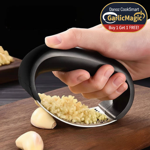 Hand using a garlic press on a wooden cutting board with garlic cloves.
