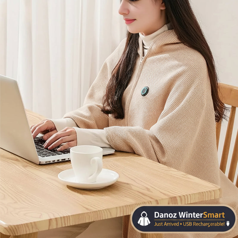 Person wearing a beige heated coat using a laptop with a cup of coffee on a wooden table.