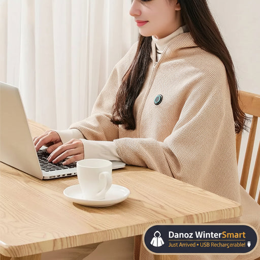 Person wearing a beige heated coat using a laptop with a cup of coffee on a wooden table.