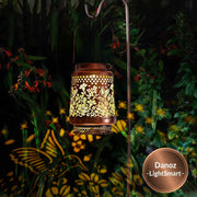 Decorative lantern with floral patterns casting shadows on a garden at night