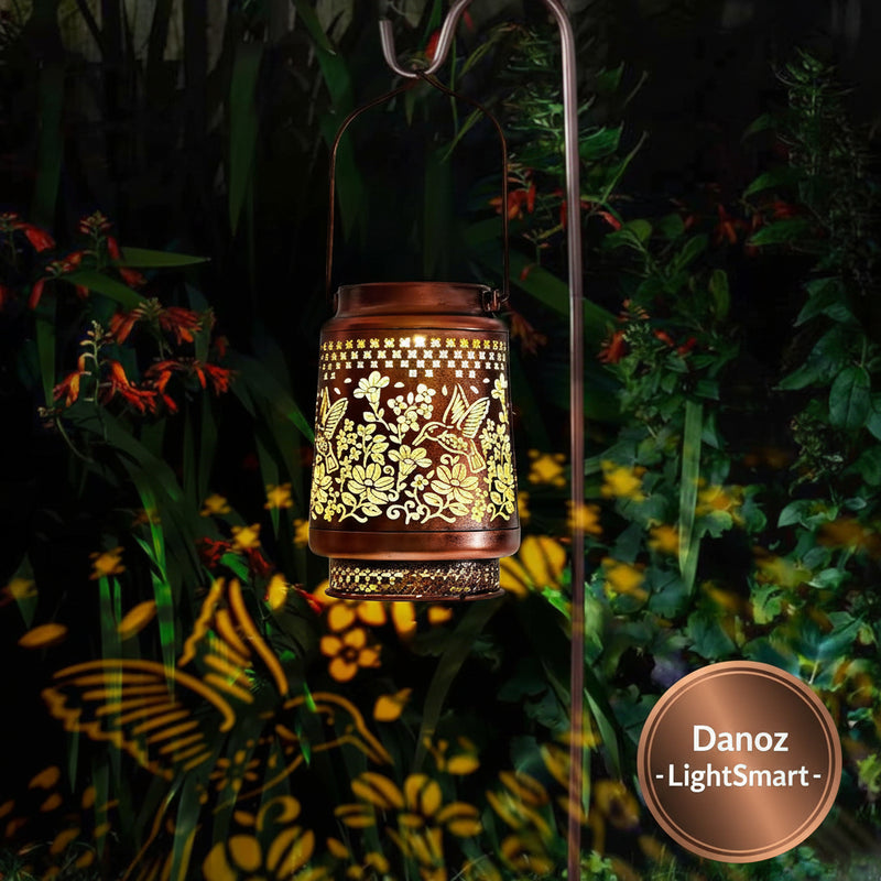 Decorative lantern with floral patterns casting shadows on a garden at night