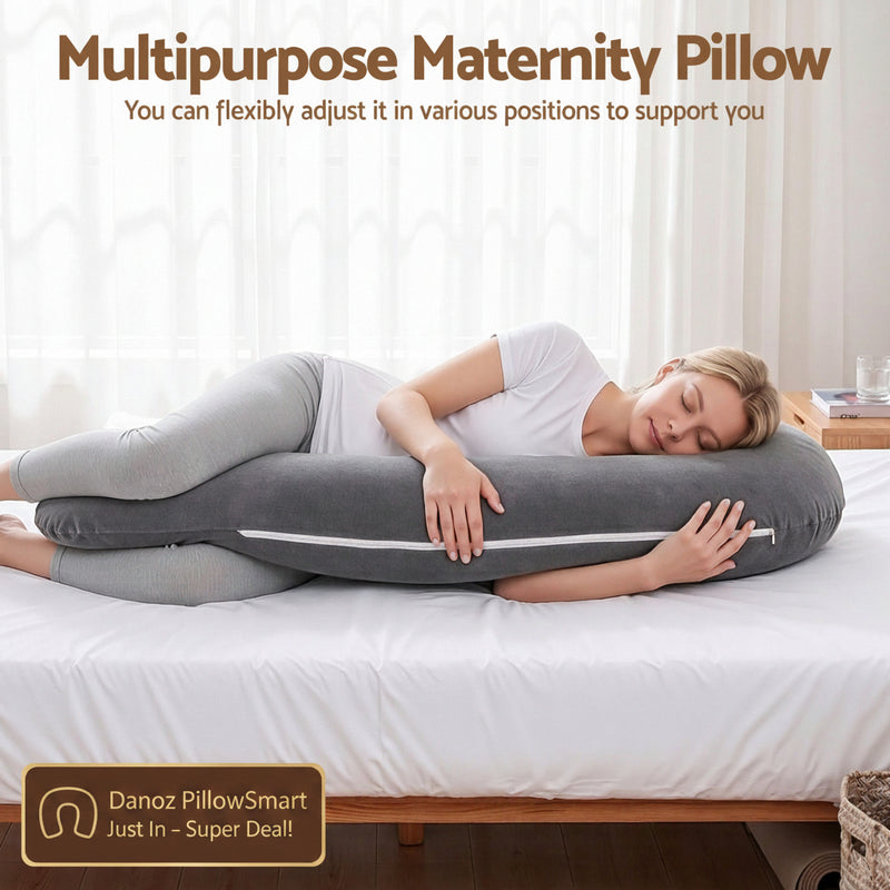 A woman lies on a bed using a dark gray multipurpose maternity pillow with a white zipper, shown in a bright bedroom setting with text at the top explaining its adjustable support function.
