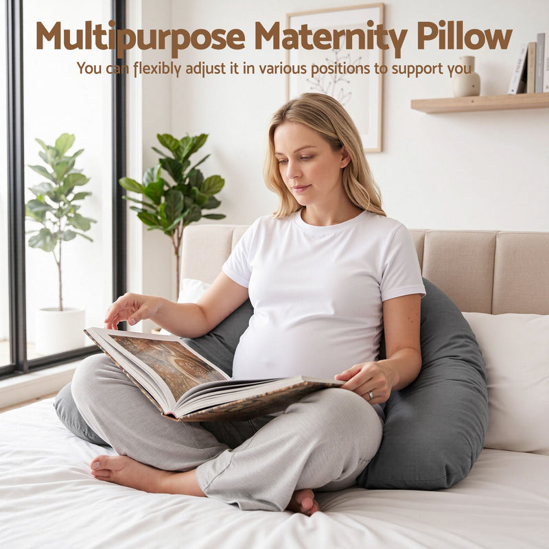 A pregnant woman sits cross-legged on a bed using a large gray multipurpose maternity pillow to support her stomach. The image includes text at the top reading 'Multipurpose Maternity Pillow' with a subtitle explaining flexibility of position.