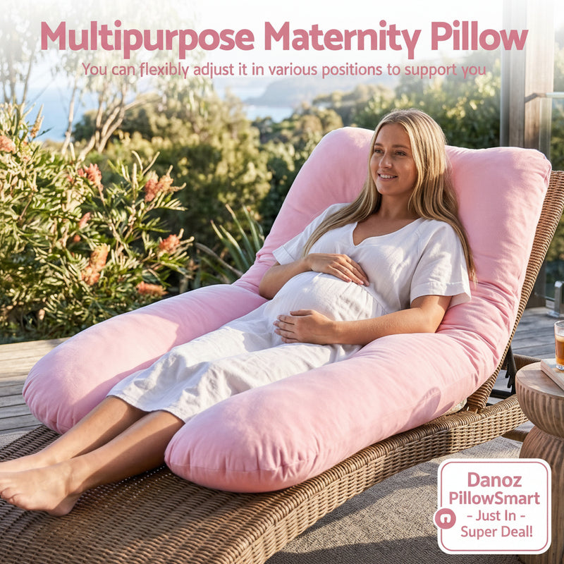 A pregnant woman reclines on a wicker lounger outdoors, supported by a large pink multipurpose maternity pillow. The scene includes greenery and a patio setting, with text at the top describing the adjustable maternity pillow.