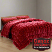 A burgundy faux mink quilt with baffle box design on a bed, accompanied by matching pillowcases.
