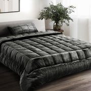 A charcoal-colored faux mink quilt with a double-sided design, displayed on a bed in a room with a neutral decor.