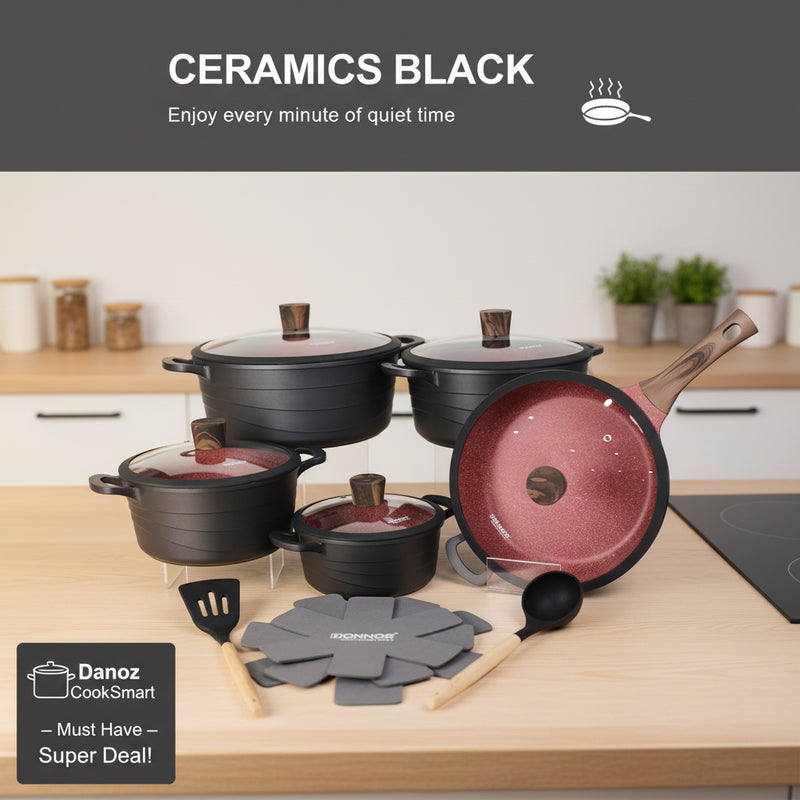 Set of black ceramic cookware with lids and utensils on a white background
