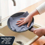 Person cleaning a frying pan with a blue cloth over a sink.