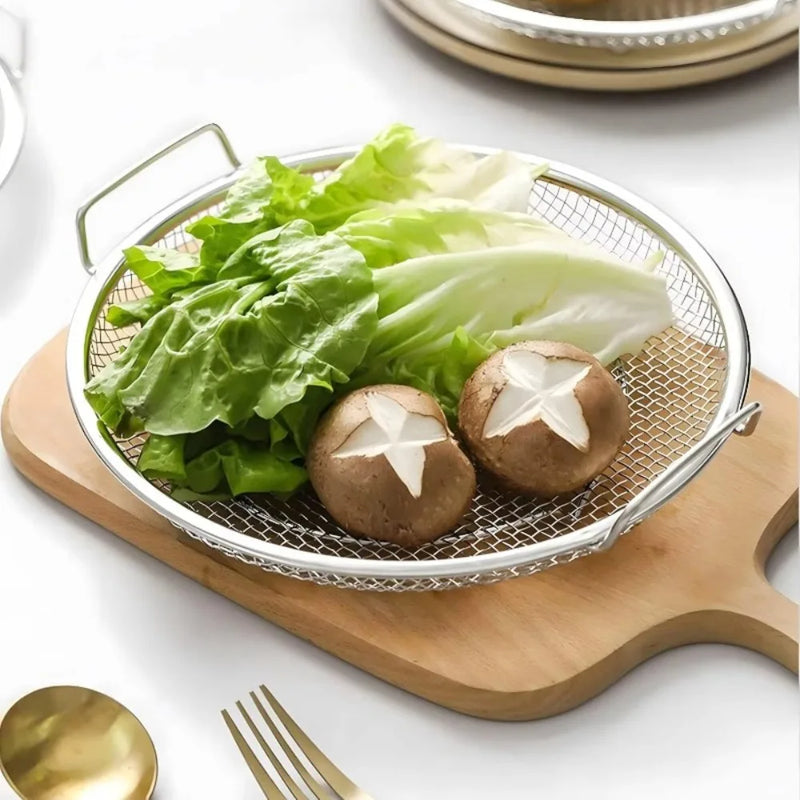 Vegetables on a metal mesh tray with a wooden cutting board and gold utensils in the background.