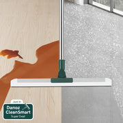 Window cleaning tool with squeegee and brush on a wooden surface and glass background
