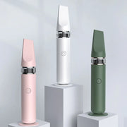 Three slim handheld electronic devices displayed on white pedestals against a light gray studio background. The devices come in three colors: pink, white, and sage green, each with a metallic silver band near the base.