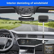 An interior car windshield demisting brush with a long handle and soft gray sponge head, shown hanging in the windshield area of a modern car dashboard. The image includes a blue banner at the top reading 'Interior demisting of windshield' and a scenic road view through the windshield.