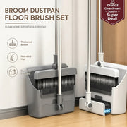 A broom, dustpan, and floor brush set shown in a home interior with wall and wood floor visible. The set includes a gray broom with a thickened head, a gray dustpan with a black bristle strip, and a white-and-gray floor brush with a blue cleaning pad.