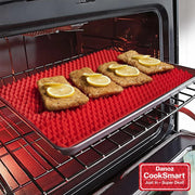 Red silicone baking mat with food items on an open oven