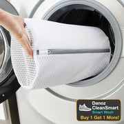White mesh laundry bag being placed into a washing machine.
