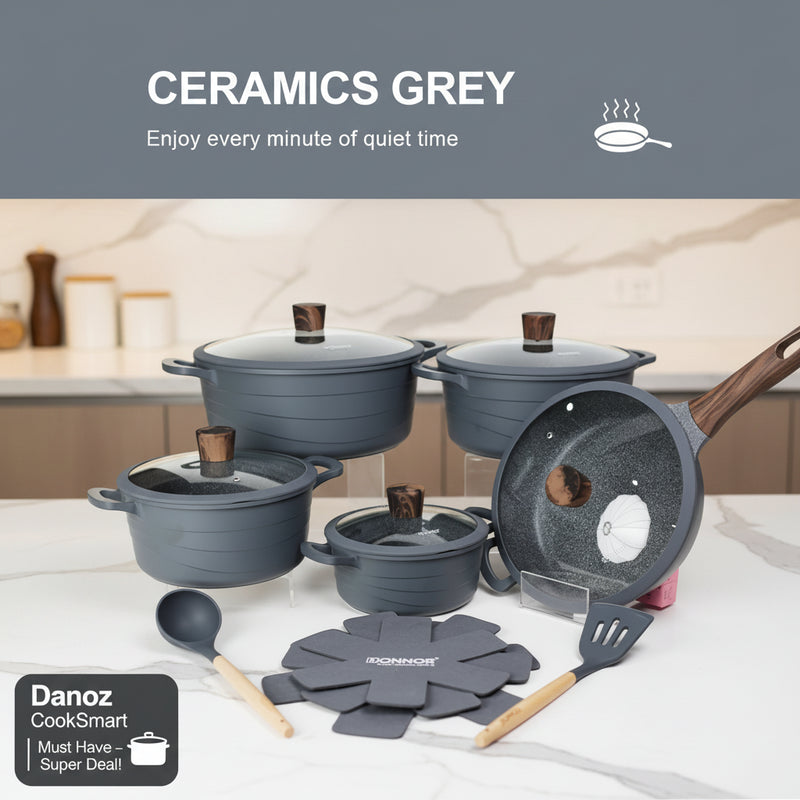 Set of grey cookware with lids, utensils, and a mat on a white background.