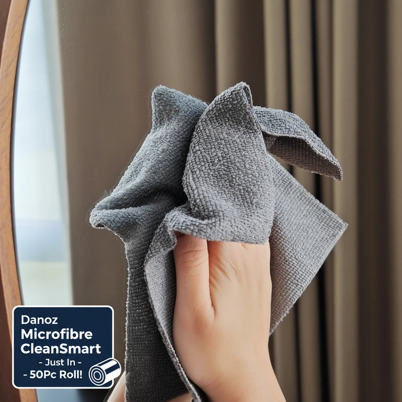 Hand holding a gray microfiber cloth against a blurred indoor background