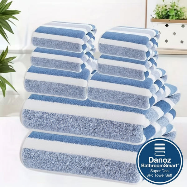 Stack of blue and white striped towels on a white surface with a plant in the background.