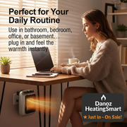 Woman using a laptop at a desk with a small heater emitting warmth.