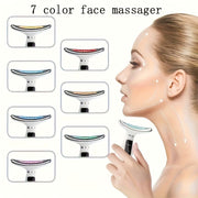 Woman using a 7-color face massager with color options displayed.