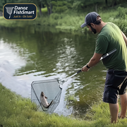 Man fishing by a pond with a fish in a net