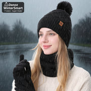Person wearing a black knit beanie with a pom-pom and black gloves on a white background