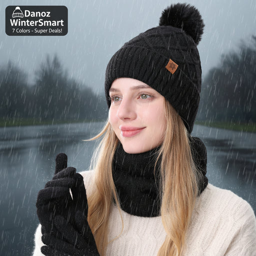 Person wearing a black knit beanie with a pom-pom and black gloves on a white background
