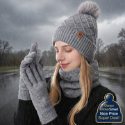 Person wearing a gray knit hat with a pom-pom, scarf, and gloves on a white background