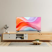 A modern flat-screen TV with a colorful abstract display sits on a light wood and white media console in a minimalist living room setting.