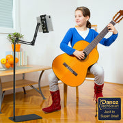 Child playing guitar with a music stand in a room with a desk and plants.