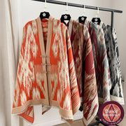 Four patterned scarves hanging on a rack with a white curtain in the background.