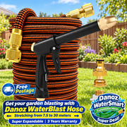 A green expandable garden hose coiled on grass with a black spray nozzle and brass connectors, shown in a sunny backyard setting. A separate brass connector is placed beside the hose, and two promotional badges read 'Free Postage' and 'Danoz WaterSmart Expandable Hose Super Deal!'.