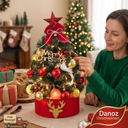 Woman adjusting an ornament on the decorated tabletop Christmas tree