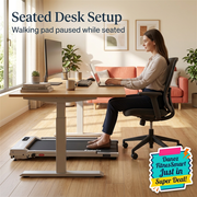 Side-view seated desk setup with treadmill forward under desk and chair wheels on wooden floor behind it; walking pad paused