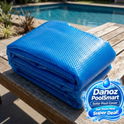 Folded blue solar pool cover at poolside with Danoz PoolSmart blue badge